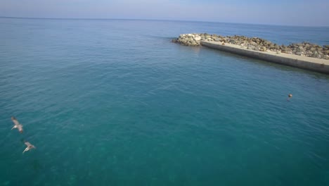 Drone-view-of-a-rock-breakwater-on-the-green-and-calm-Caribbean-Sea