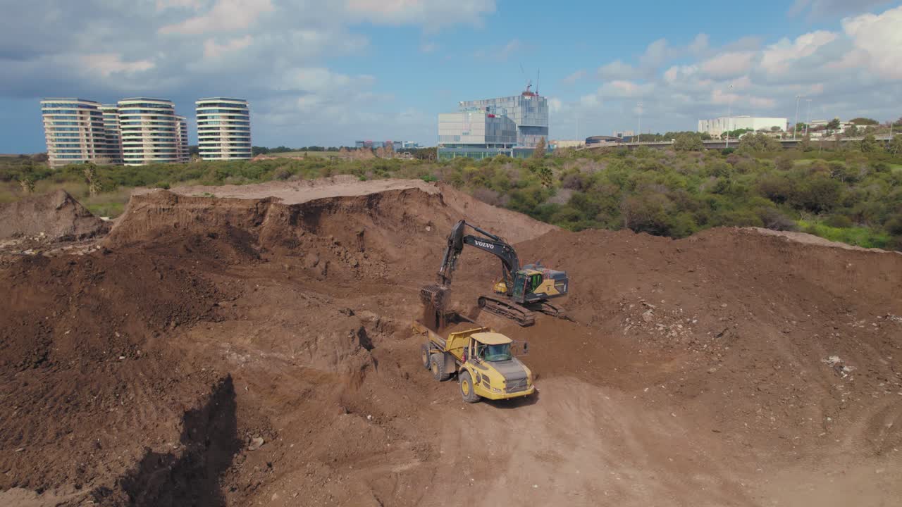una excavadora y un camión están cargando tierra en un nuevo sitio de construcción en un vecindario en un día nublado