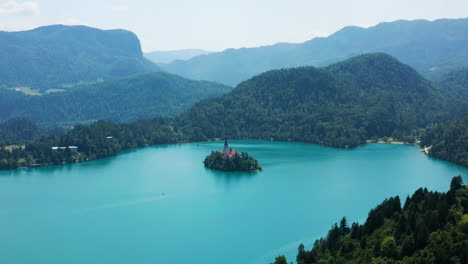 panorama of small island at the middle of lake bled with a view of mountain range in slovenia