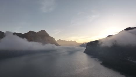 aerial view of walensee lake, switzerland, at sunrise, shrouded in mist and fog. the serene alpine panorama is framed by majestic mountains, radiating ethereal charm and tranquility.