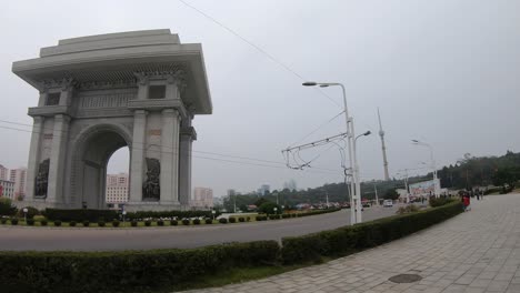 a van drives past arch of triumph. pyongyang, north korea. panning left shot