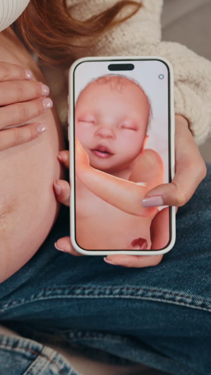 Le mani di una donna tengono uno smartphone che mostra un'immagine realistica di un bambino, con una vista ravvicinata del ventre materno durante la gravidanza