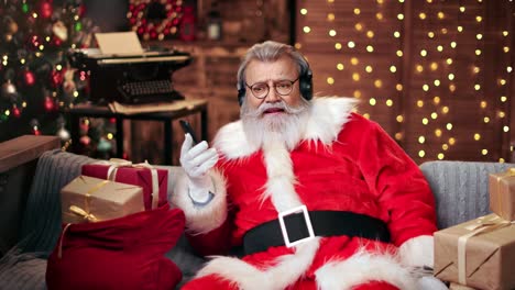 male santa claus listen music in headphones use smartphone. shot on red raven 4k cinema camera