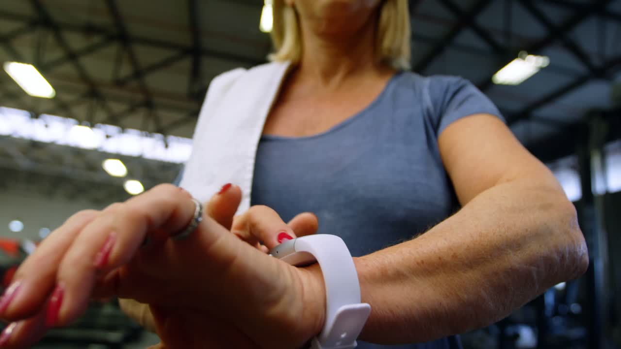 mujer mayor usando smartwatch en el estudio de fitness 4k