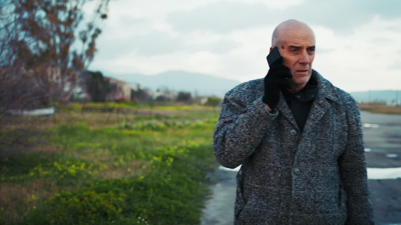 Old Man Trying to Make a Call During a Winter Walk