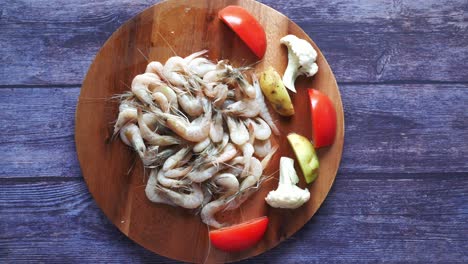 camarón crudo con verduras en una tabla de cortar de madera