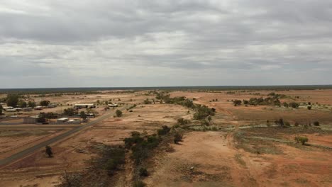 drone ascendiendo sobre un paisaje desierto que muestra una muy pequeña ciudad del interior de australia