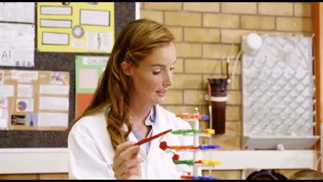 Teacher-assisting-school-kids-with-molecule-model-in-laboratory