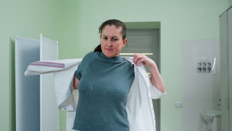 elegant pharmacist wears work uniform inside brightly lit medical room then walks towards computer workstation to operate system with focus and professionalism, preparing for patient consultations