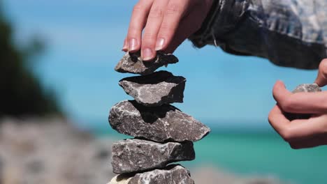 Frau-Stapelt-Zen-Steine-Auf-Einer-Insel