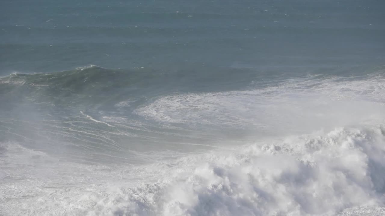 Massive waves crashing onto the shore of Nazare, Portugal, showcasing nature's power