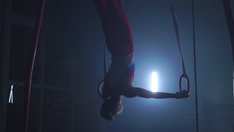 gymnast performing gymnastic cross exercise on gymnastic rings. shot in slow motion.