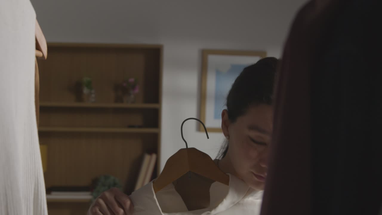 직장 면접을 위해 옷장에서 비즈니스 정장을 선택하는 집에 있는 젊은 여성 1