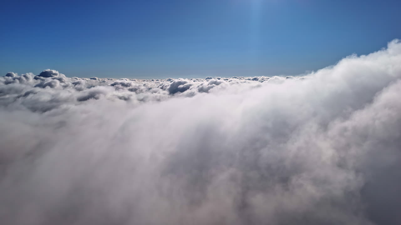 Drone above thick cloud layer revealing soft white textures and distant horizon, aerial pullback