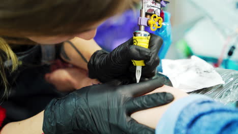 unrecognized tattooist putting the lines on the sketch. customer getting a tattoo on a hand. close up.