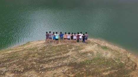 group of happy friends embracing while standing on lake shore at danao lake natural park in leyte, philippines