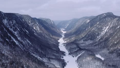 Toma-Aérea-épica-Del-Fiordo-Cubierto-De-Nieve,-Invierno-En-El-Bosque-Boreal-Canadiense