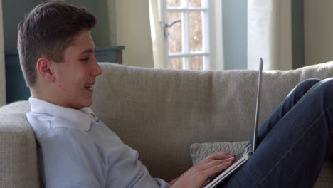 Teenage-Boy-Sitting-On-Sofa-Using-Laptop-At-Home-Shot-On-R3D