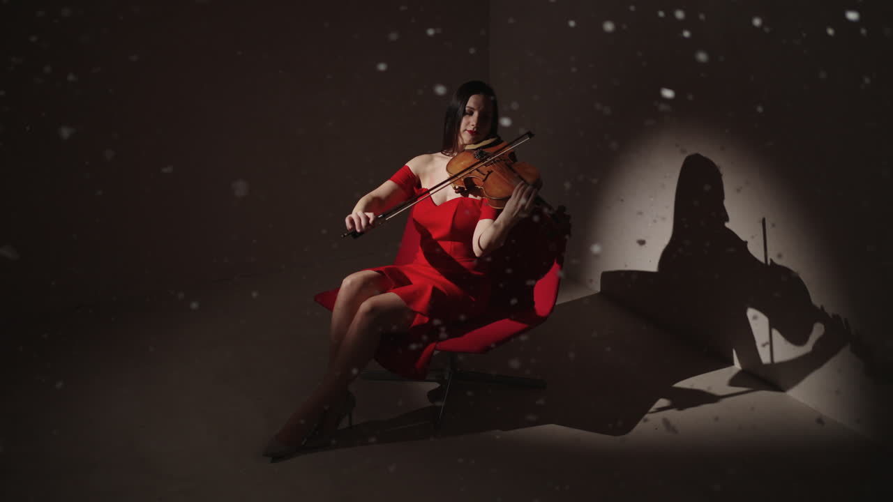 Violinista in abito rosso che suona il violino in un ambiente da studio invernale