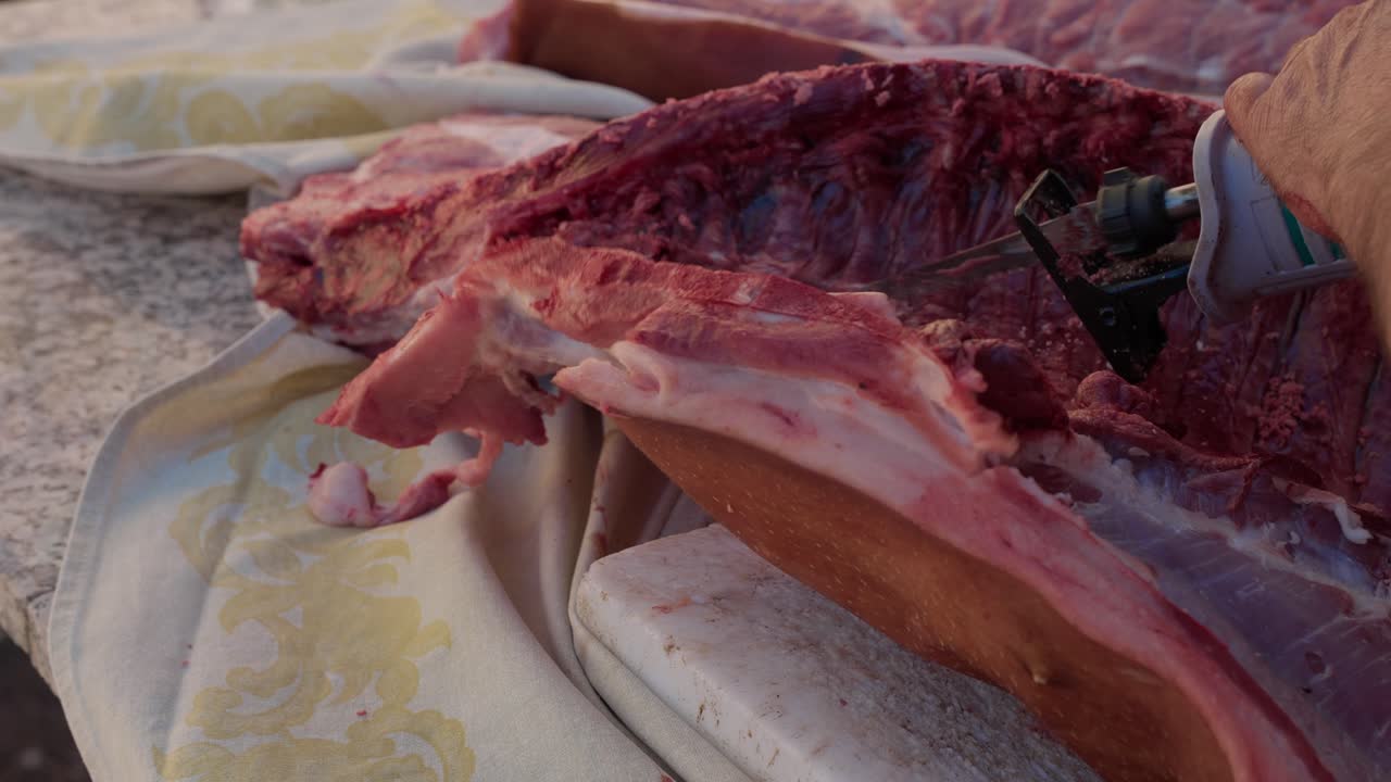 Cutting pork carcass with saw during traditional slaughter - slow motion