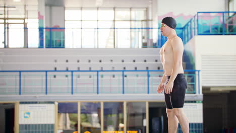 Male-swimmer-jumping-off-the-starting-block-into-the-pool