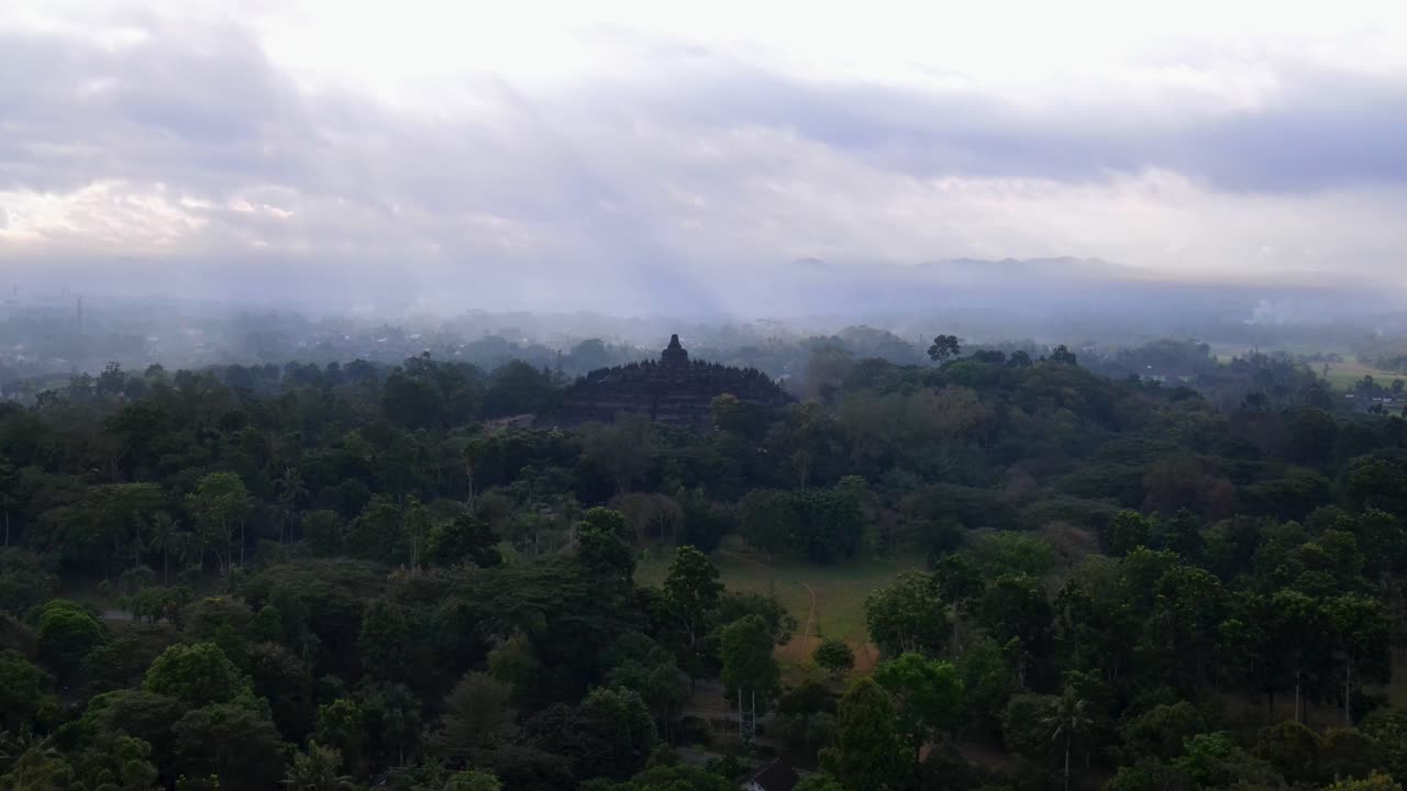 Veduta aerea del tempio di Borobudur circondato dagli alberi della foresta con i raggi del sole al mattino