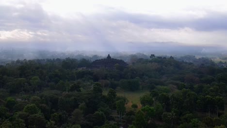 aerial view of borobudur temple surrounded by trees of forest with sunray in the morning