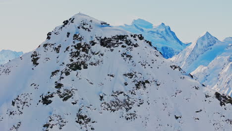 ski mountaineers atop bec des rosses, val de bagnes, with grand combin behind, ready to drop into the legendary north face.