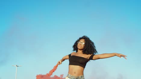 young woman dancing outside with smoke grenade at sunset on rooftop parking garage