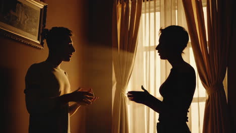 silhouettes of a man and woman engaged in conversation by a window