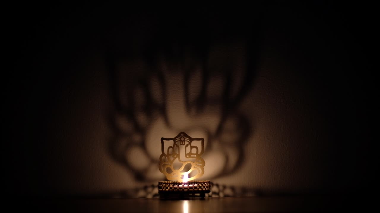 Shadow and light dance, play reflection on wall of Ganesha cutout, also Ganapati Vinayaka, one of the best-known and most worshipped deities in the Hindu pantheon, specially during Diwali