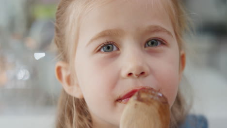 happy little girl licking spoon tasting delicious chocolate pudding enjoying homemade treats in kitchen 4k