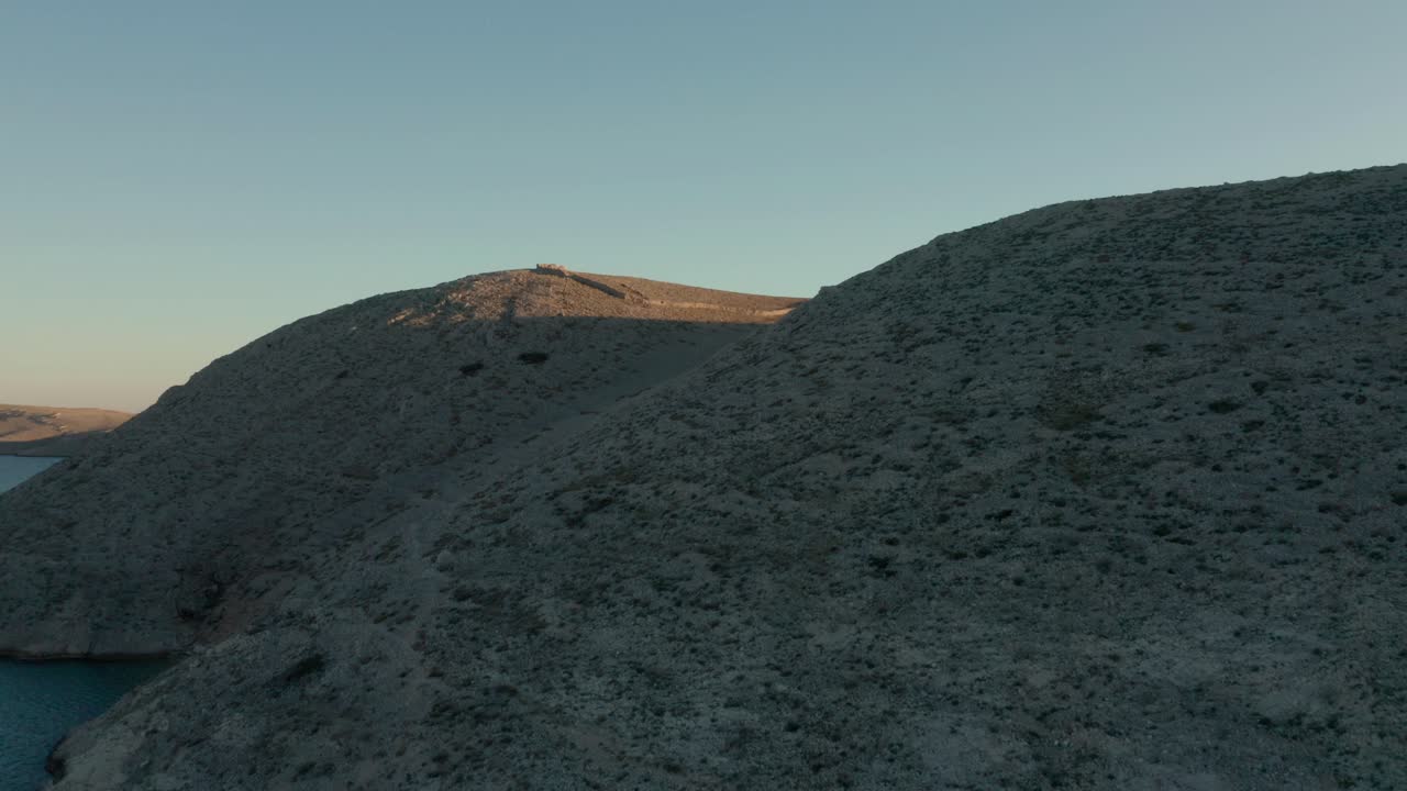 volando sobre el paisaje adriático en croacia con paredes rocosas hechas, marcando un área durante la puesta de sol - toma aérea