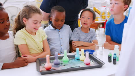 niños y el maestro mirando frascos en el experimento de ciencia