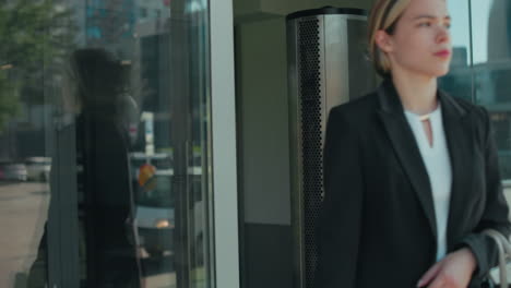 remote worker walks out of restaurant with reflection of parked cars and urban buildings on glass door, city street in background, focus on movement, and professional casual environment