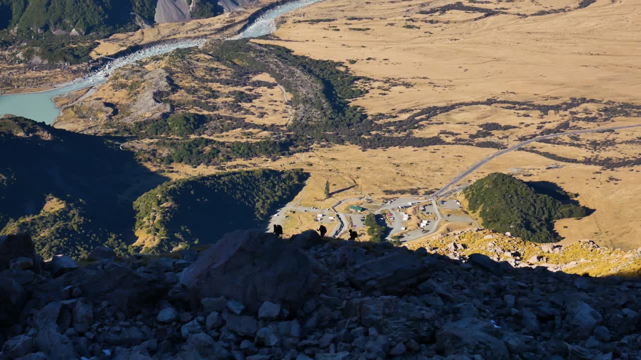 massive valley with tiny silhouetted hikers on ridge