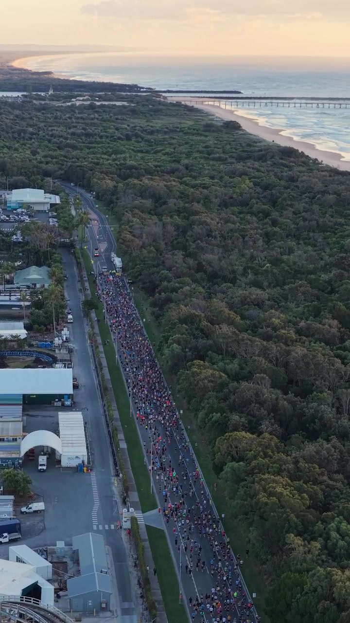 Riprese aeree verticali che avanzano sopra il percorso della Maratona della Gold Coast lungo la costa di Southport, Queensland, Australia.