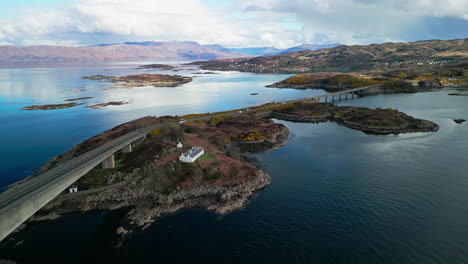 Quaint-cottage-sits-on-cliff-by-Skye-bridge-as-travelers-explore-the-natural-beauty-of-Scotland