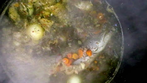 top view of a boiling pot with a fish and vegetables, making soup