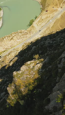 río y campamento en el fondo de la montaña drone fpv lecho del río sinuoso cerca de la carretera y la base turística en las tierras altas alto acantilado empinado en el valle soleado