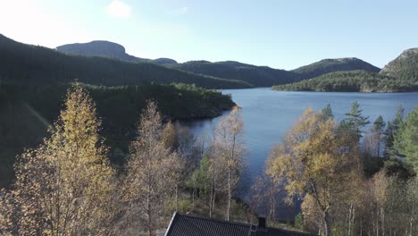 Hildremsvatnet,-Condado-De-Trondelag,-Noruega---Una-Escena-Serena-De-Un-Lago-Rodeado-De-Exuberante-Vegetación-Con-Una-Cabaña-De-Pescadores-Situada-En-Su-Orilla---Drone-Volando-Hacia-Adelante