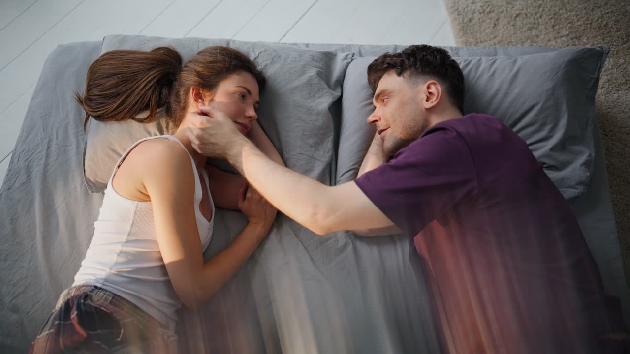 Love couple lying mattress enjoying wake up together top view. Enamoured pair