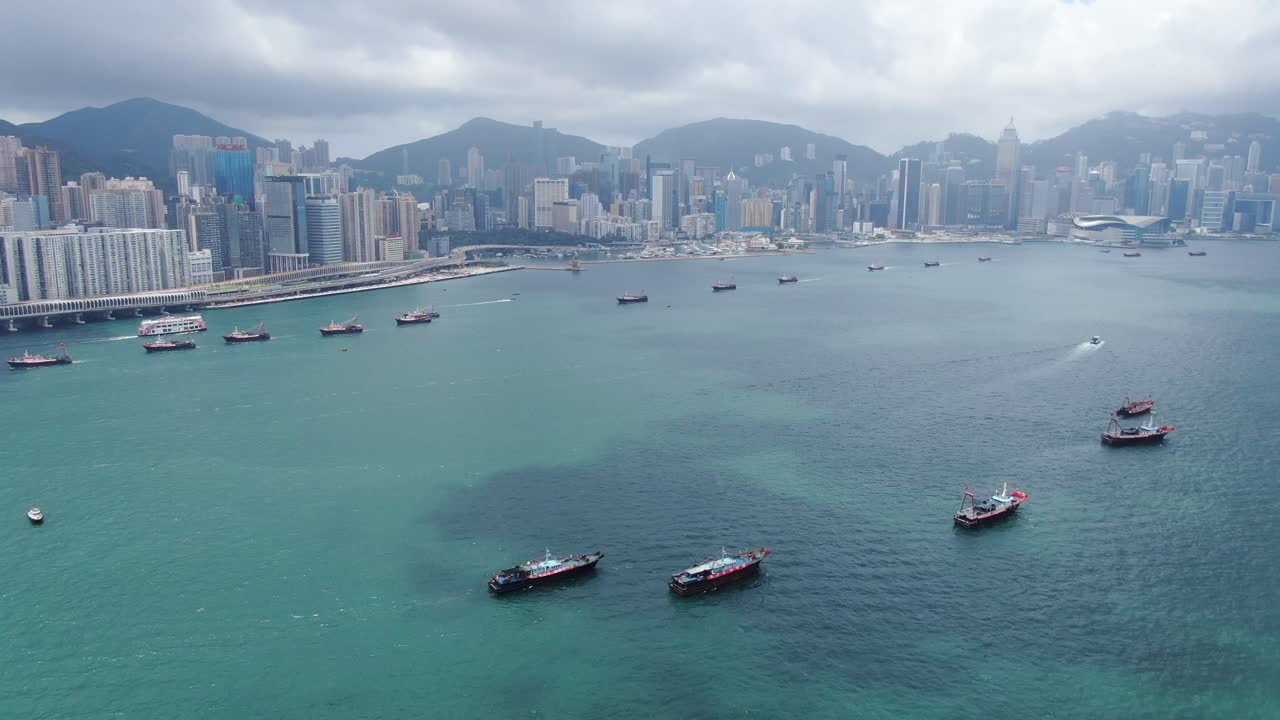 convoy de barcos de pesca locales que causan en la bahía victoria de hong kong, con el horizonte de la ciudad en el horizonte, vista aérea