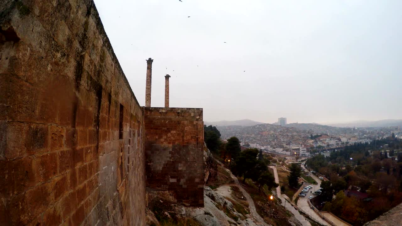 Urfa Kalesi surları panoraması, iki sütun ve şehir, bulutlu kış günü.