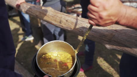 typical argentine gastronomy meeting, serving locro stew in cooking pots, slowmotion