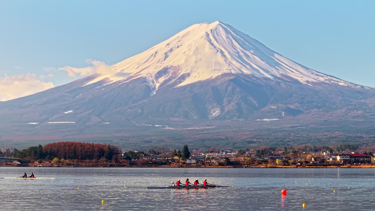 Aerial drone view of a rowing team of four people with a coxswain seated at the front practicing on Lake Kawaguchiko, with Mount Fuji on the background