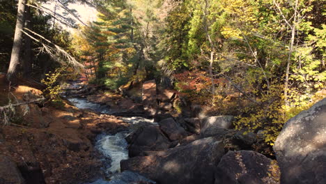 drone flyover river flowing along rocky landscape, surrounded by dense vegetation, tranquil natural scene