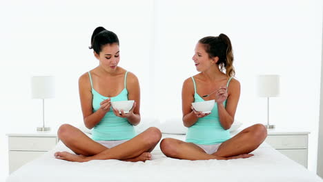 Content-young-women-eating-cereal-sitting-on-bed