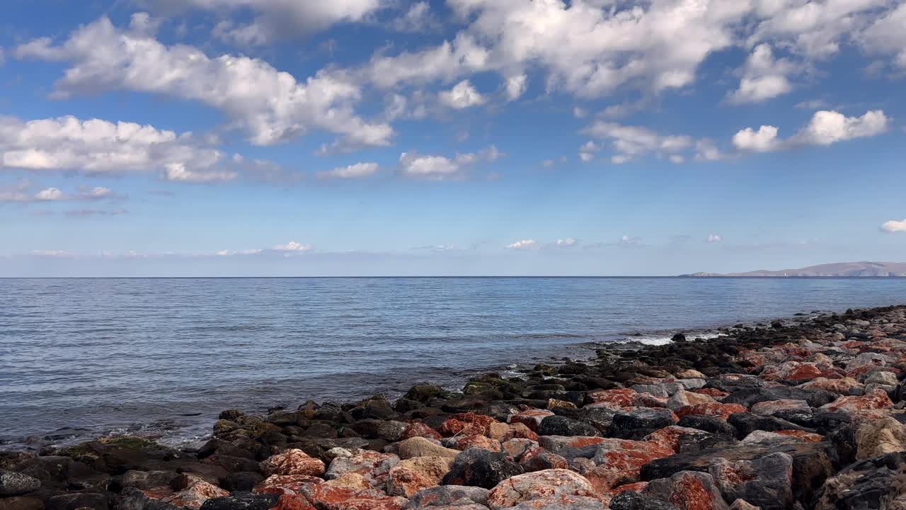 Rocky coastline on Crete Island Greece with calm sea, blue sky, and scattered clouds