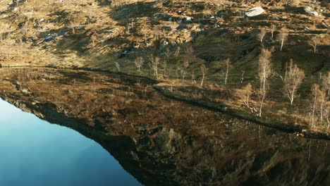 mountain covered in moss and lichen reflected in the mirrorlike surface of the lake